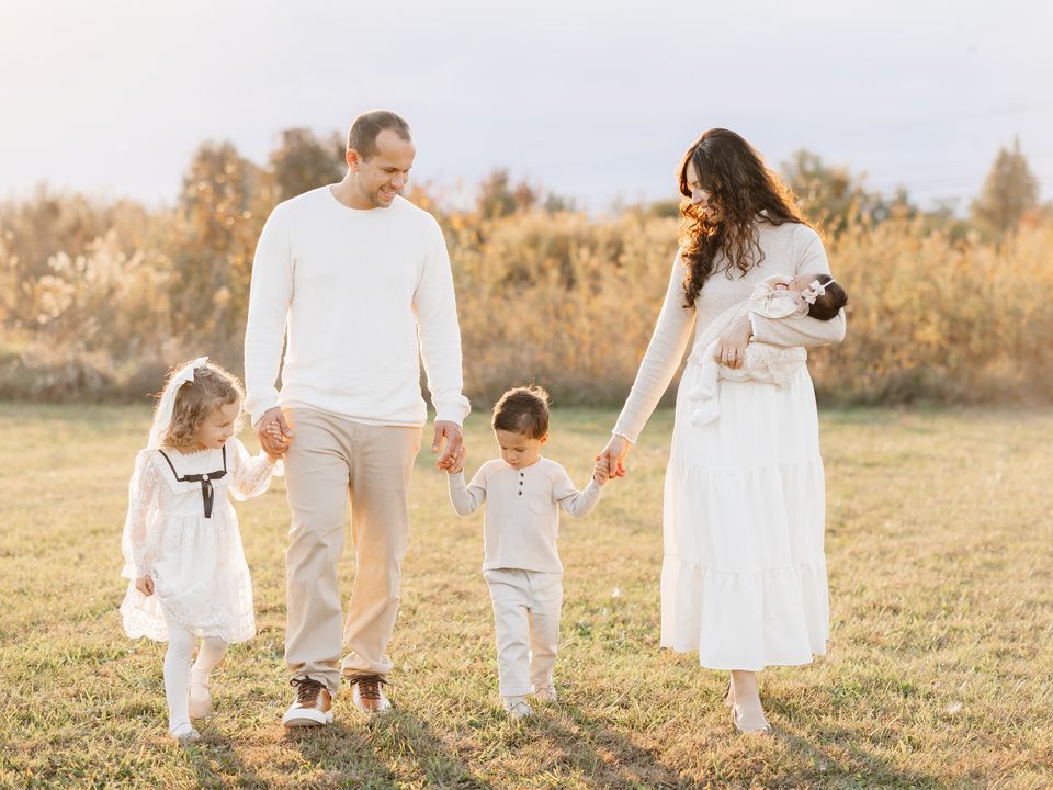 Daniel and his family walking hand in hand through a field in the fall.