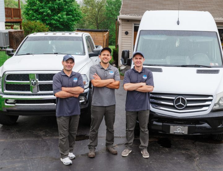 Daniel's Home Improvement crew members posing with arms crossed in front of their professional fleet, showcasing teamwork and readiness.