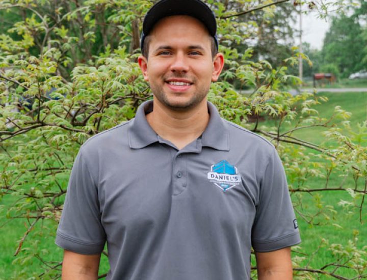 A smiling member of the Daniel's Home Improvement team standing outdoors with trees in the background, showcasing professionalism and approachability.